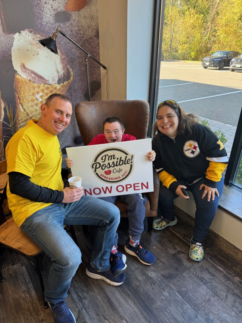 Family with their son who has a disability showing off the new window sign of the cafe before its grand opening on Saturday October 25, 2025.