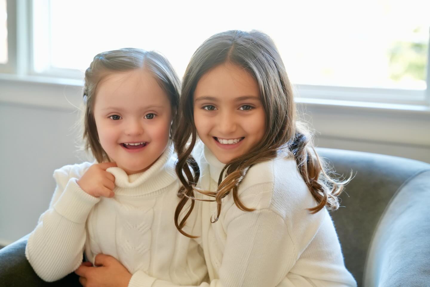 Photo of siblings Addie and Charlee sitting together and smiling with joy. This photo is symbolic of the spirit of National Siblings Day, which is about celebrating the bond between siblings and which is the focus of this blog post