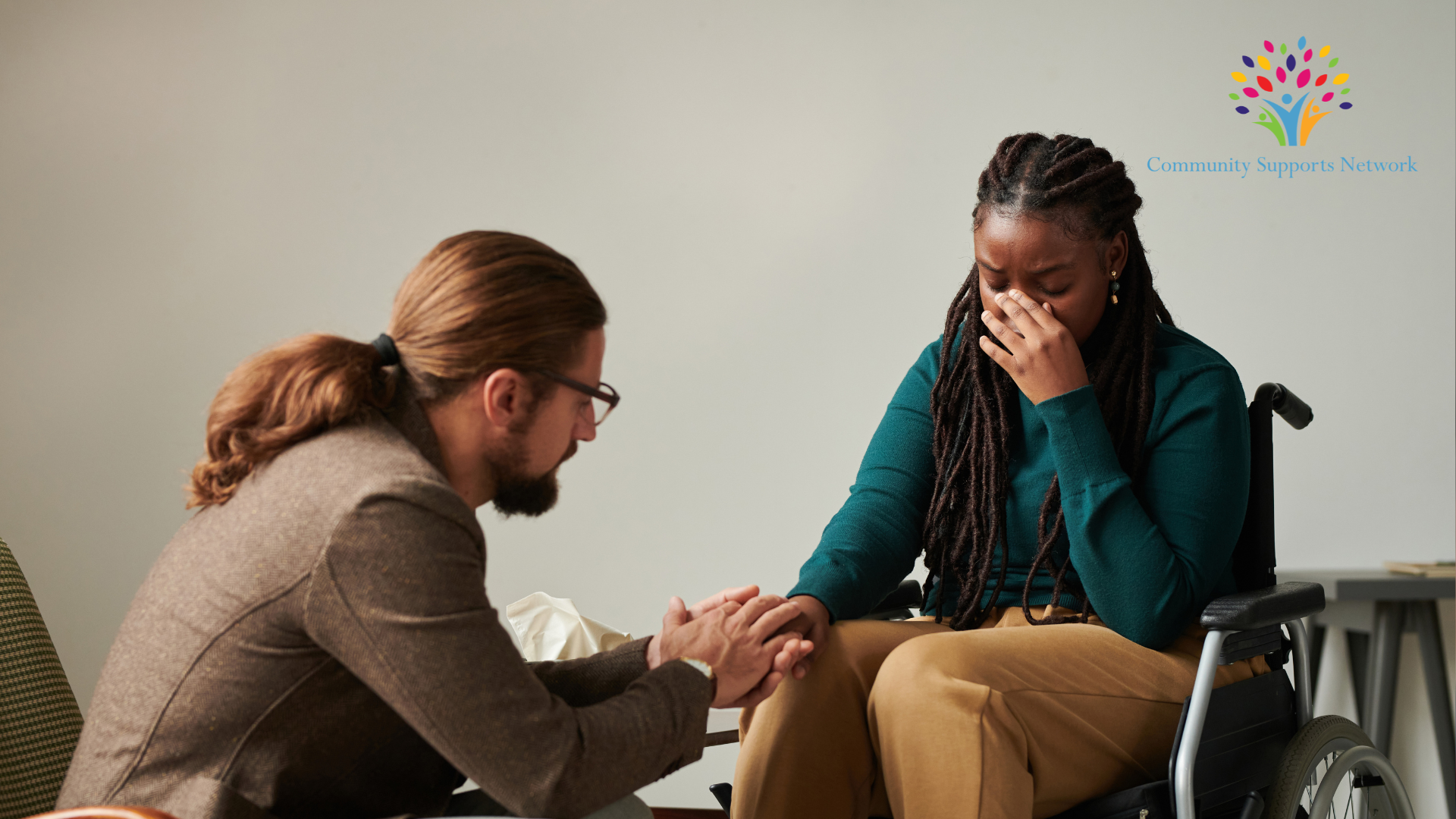 Photo of a caregiver comforting a person with a disability who is undergoing mental stress arising from the challenges she faces on a daily basis.  This image is illustrative of the importance of recognizing Mental Health Awareness month, which helps raise awareness on topics covered in our blog post today. 