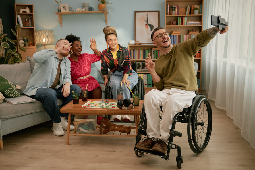 Photo of a group of friends including a person with a disability, having a laugh together while posing for the photo. This scene demonstrates inclusivity which is a key part of this blog post about friendship and disability.